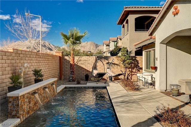 view of pool with pool water feature, a mountain view, and a patio