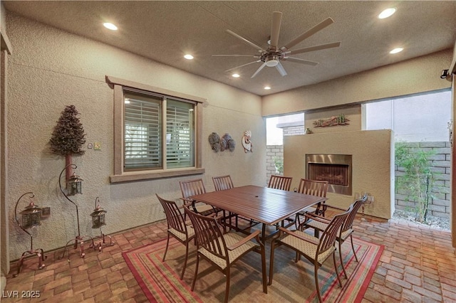 dining space with a fireplace and ceiling fan