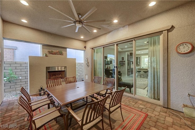 dining space with ceiling fan and a fireplace