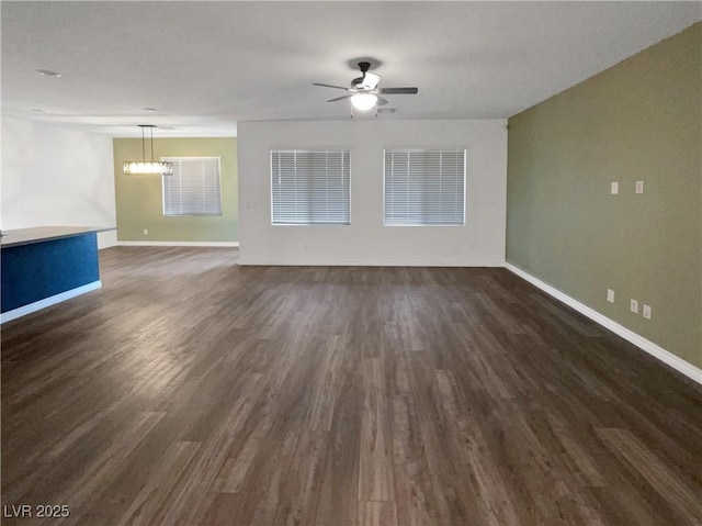 spare room featuring dark wood-type flooring and ceiling fan with notable chandelier