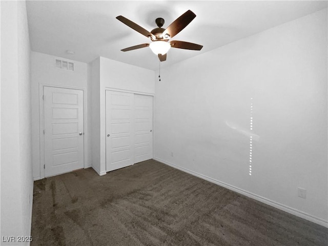 unfurnished bedroom featuring ceiling fan, dark carpet, and a closet