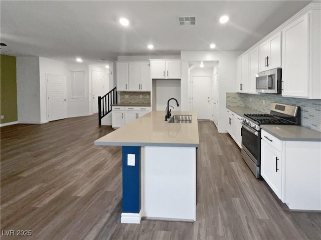 kitchen with white cabinets, appliances with stainless steel finishes, an island with sink, and sink