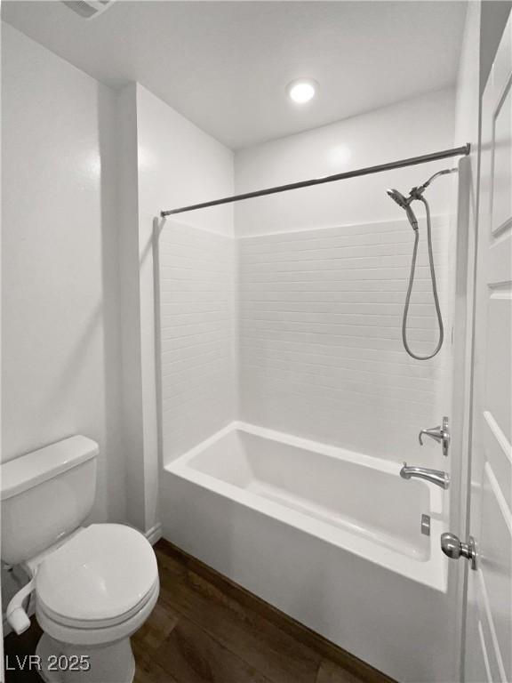 bathroom with shower / bath combination, wood-type flooring, and toilet