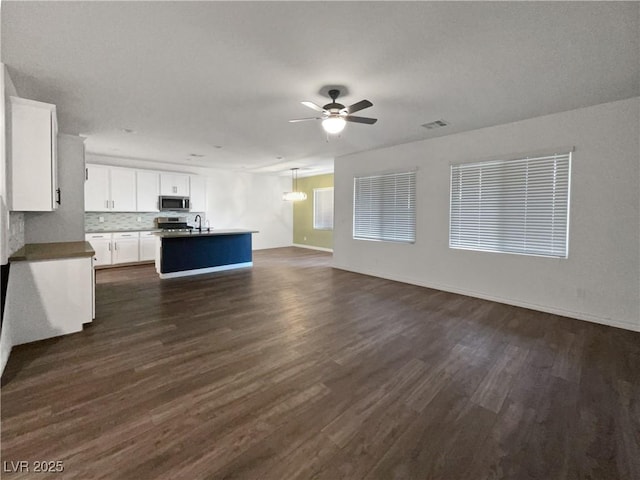 unfurnished living room featuring ceiling fan, dark hardwood / wood-style floors, and sink