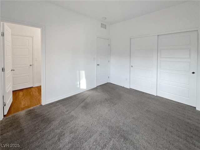 unfurnished bedroom featuring dark colored carpet and a closet