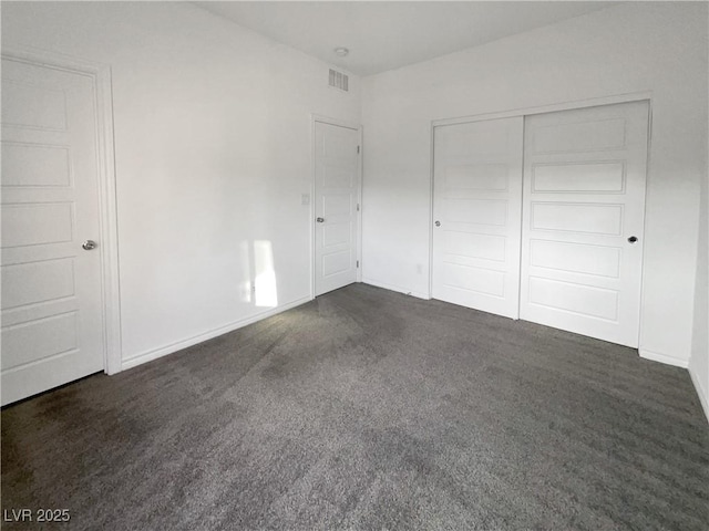 unfurnished bedroom featuring dark carpet and a closet