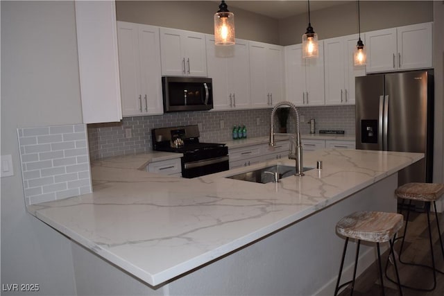 kitchen with a breakfast bar, white cabinetry, sink, and appliances with stainless steel finishes