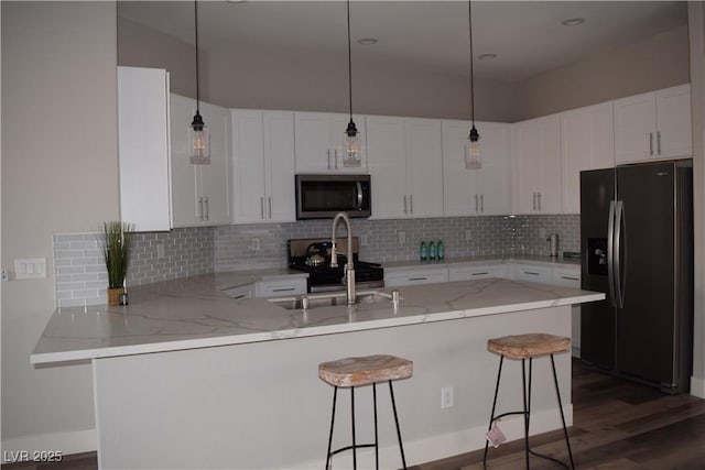 kitchen featuring white cabinets, a kitchen bar, kitchen peninsula, and stainless steel appliances