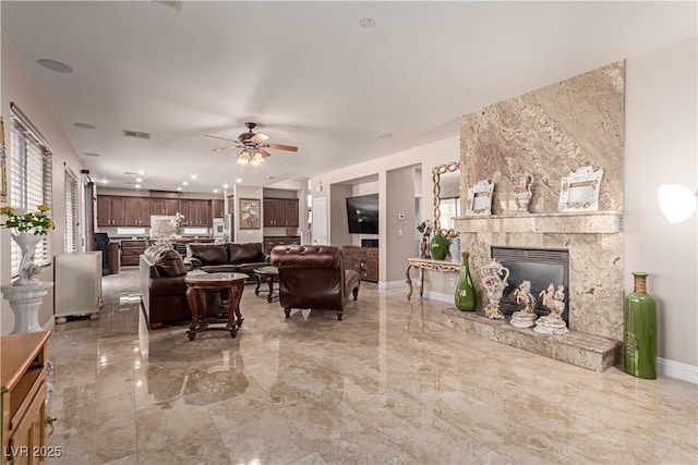 living room with ceiling fan and a stone fireplace