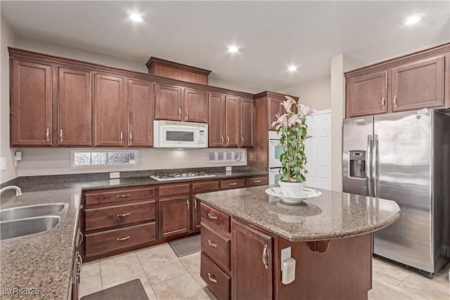 kitchen with a center island, stainless steel appliances, dark stone counters, sink, and light tile patterned flooring