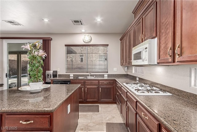 kitchen featuring sink, white appliances, and dark stone countertops