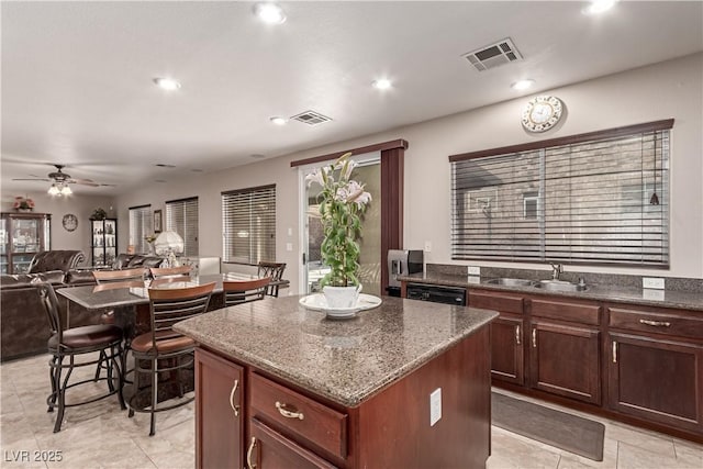 kitchen with ceiling fan, a center island, sink, black dishwasher, and dark stone counters