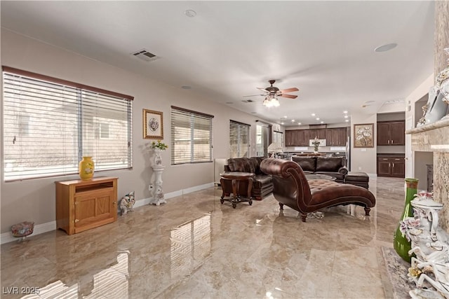 living room featuring ceiling fan, plenty of natural light, and a premium fireplace