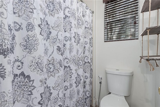 bathroom with curtained shower and toilet