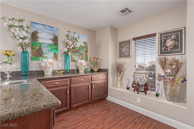 interior space with dark hardwood / wood-style flooring, sink, and dark stone counters