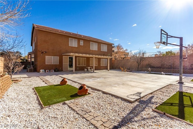 rear view of house with basketball court and a patio area