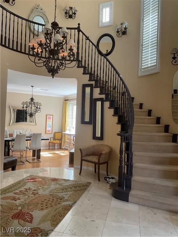 staircase featuring tile patterned floors, a towering ceiling, and an inviting chandelier