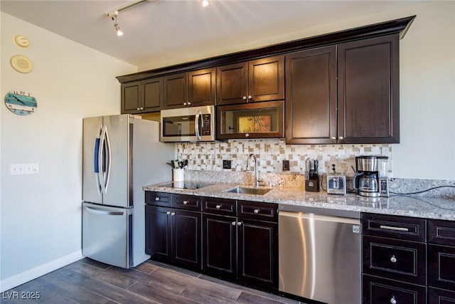 kitchen featuring decorative backsplash, appliances with stainless steel finishes, light stone counters, dark brown cabinets, and sink