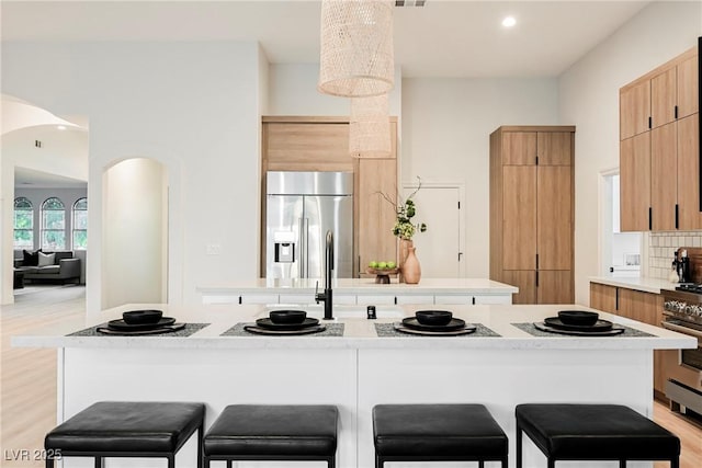 kitchen featuring decorative backsplash, a kitchen breakfast bar, a kitchen island, oven, and built in fridge