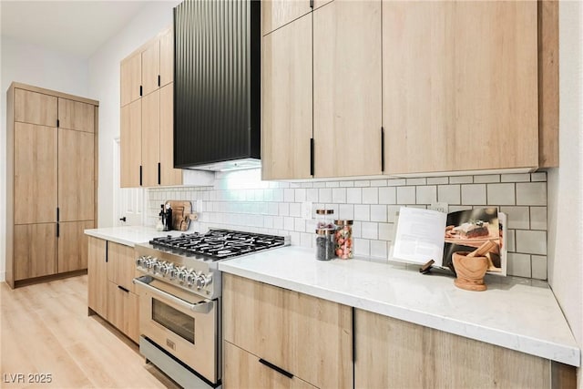 kitchen featuring light brown cabinets, high end range, and range hood