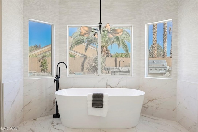 bathroom with a bathing tub, a notable chandelier, and tile walls