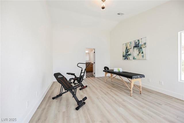 exercise area featuring vaulted ceiling and light wood-type flooring