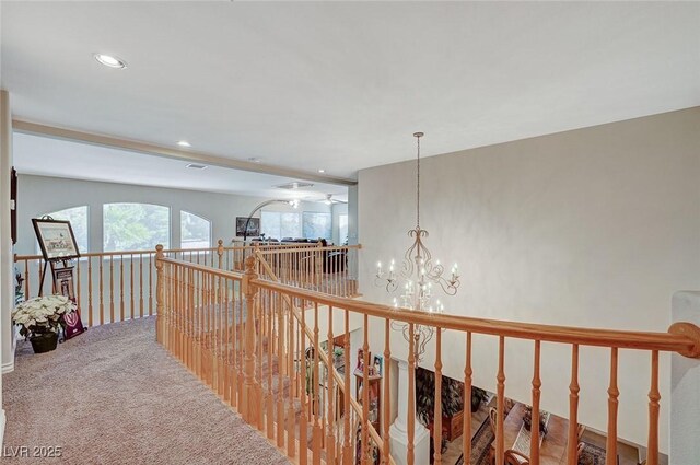 hall with beam ceiling, carpet floors, and an inviting chandelier