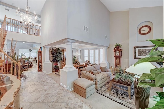 living room featuring ornate columns, a towering ceiling, and a chandelier