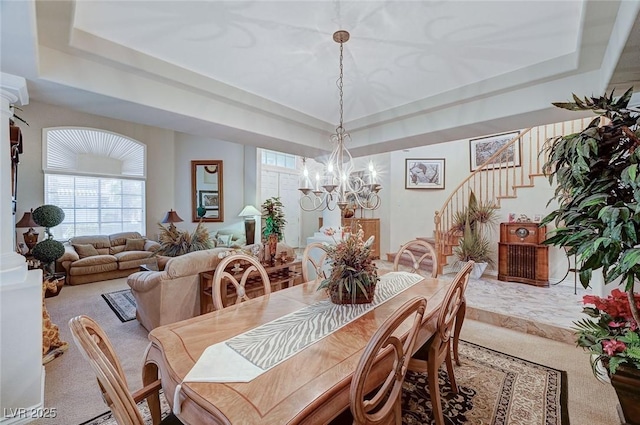 dining space featuring a notable chandelier, carpet floors, and a tray ceiling