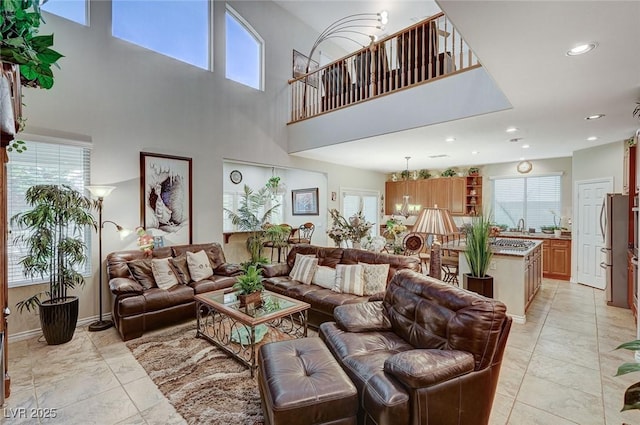 living room with a towering ceiling, a healthy amount of sunlight, and a notable chandelier