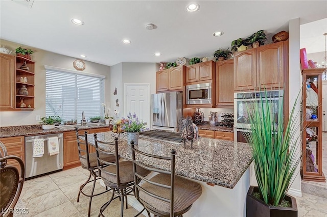 kitchen featuring sink, a breakfast bar area, dark stone countertops, a kitchen island, and stainless steel appliances