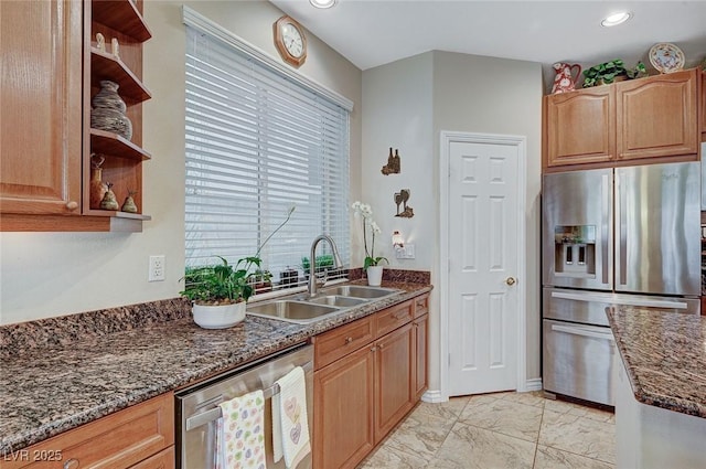 kitchen featuring appliances with stainless steel finishes, dark stone countertops, and sink