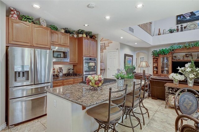 kitchen with a kitchen breakfast bar, a kitchen island, stainless steel appliances, and stone counters