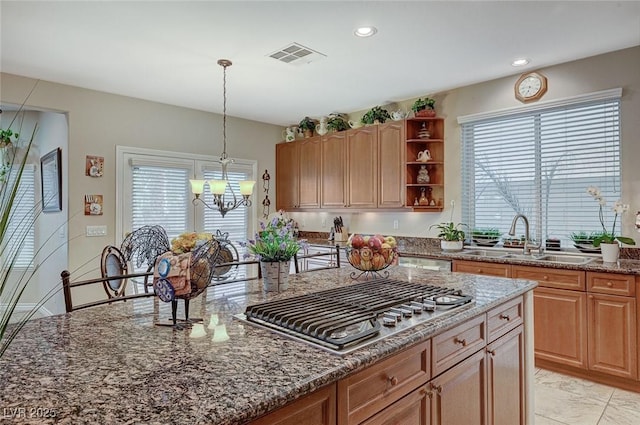 kitchen with a healthy amount of sunlight, sink, stainless steel gas cooktop, and a chandelier