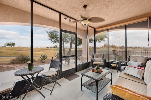 sunroom with a wealth of natural light, ceiling fan, and a rural view