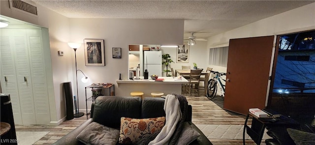 living room featuring a textured ceiling, light hardwood / wood-style floors, and ceiling fan