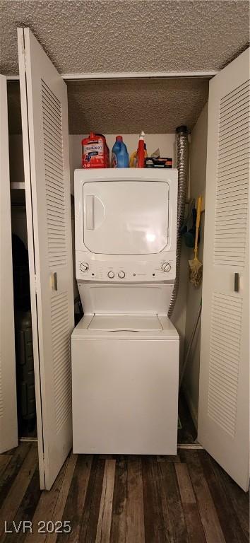 laundry area featuring stacked washer / dryer, dark hardwood / wood-style flooring, and a textured ceiling