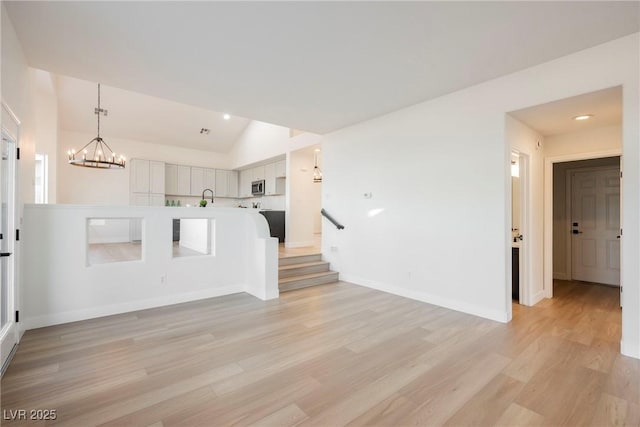 unfurnished living room with lofted ceiling, sink, and light hardwood / wood-style flooring