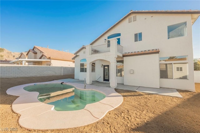 back of house with a fenced in pool, a patio area, and a balcony