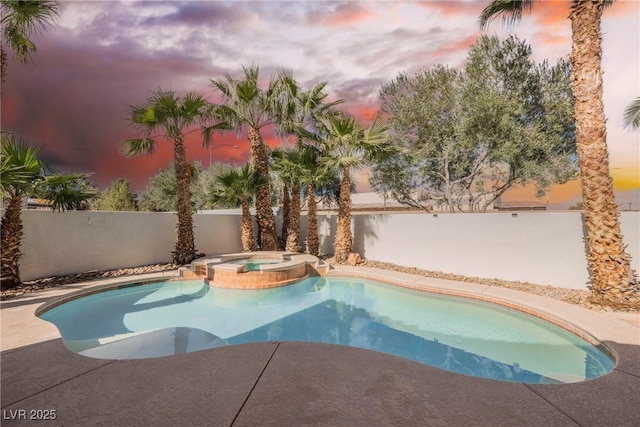 pool at dusk with an in ground hot tub