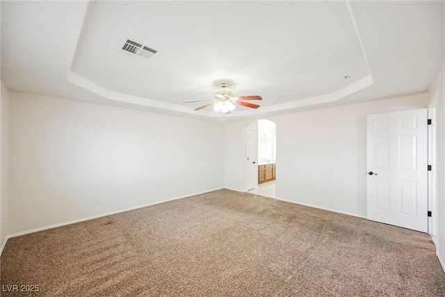 carpeted empty room featuring a raised ceiling and ceiling fan