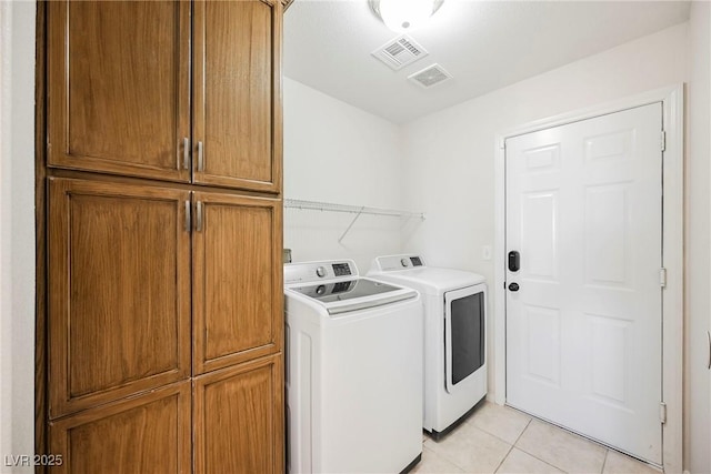 washroom with cabinets, independent washer and dryer, and light tile patterned flooring