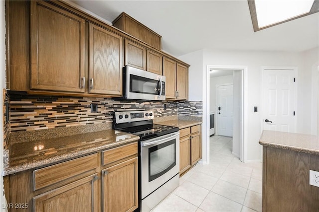 kitchen with backsplash, dark stone countertops, light tile patterned floors, and stainless steel appliances