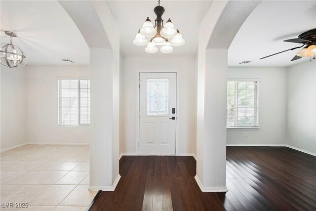 entrance foyer with hardwood / wood-style floors, ceiling fan with notable chandelier, and plenty of natural light