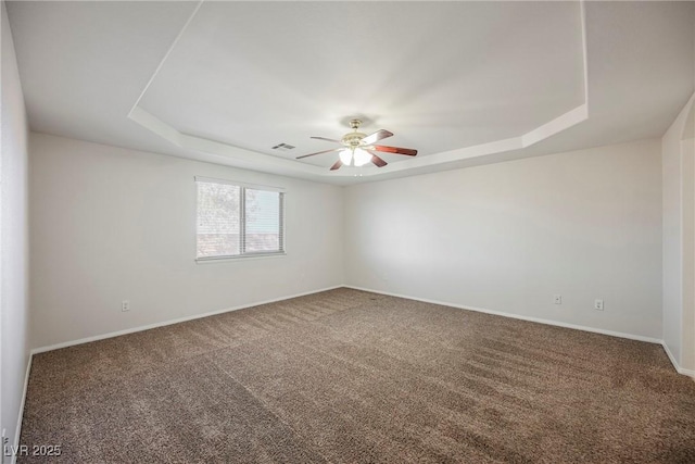 carpeted empty room with a raised ceiling and ceiling fan