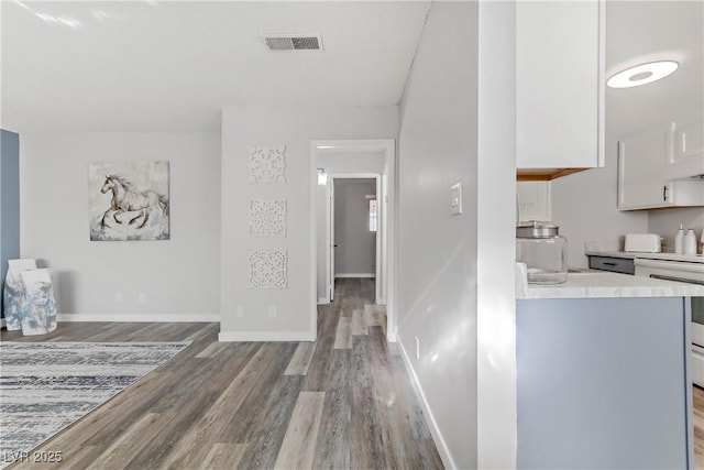 hallway with visible vents, light wood-style flooring, and baseboards