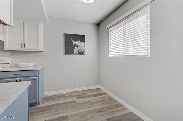 kitchen featuring gray cabinetry, baseboards, light countertops, light wood-style flooring, and white cabinetry