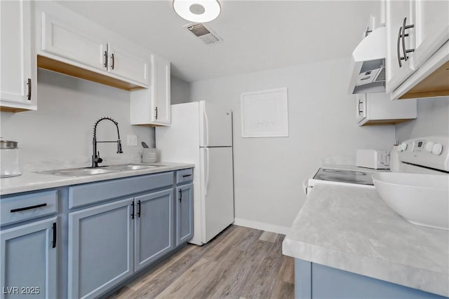 kitchen featuring a sink, visible vents, light countertops, and freestanding refrigerator