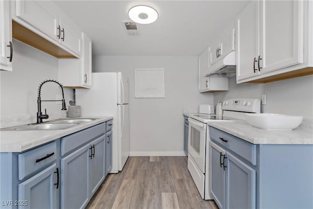 kitchen with a sink, light countertops, under cabinet range hood, and white range with electric cooktop