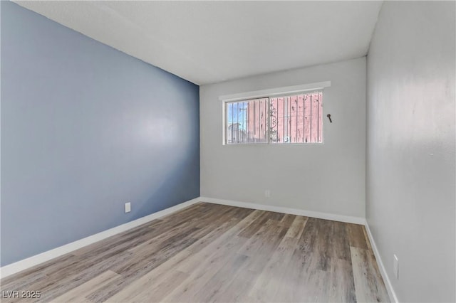 spare room with wood finished floors and baseboards